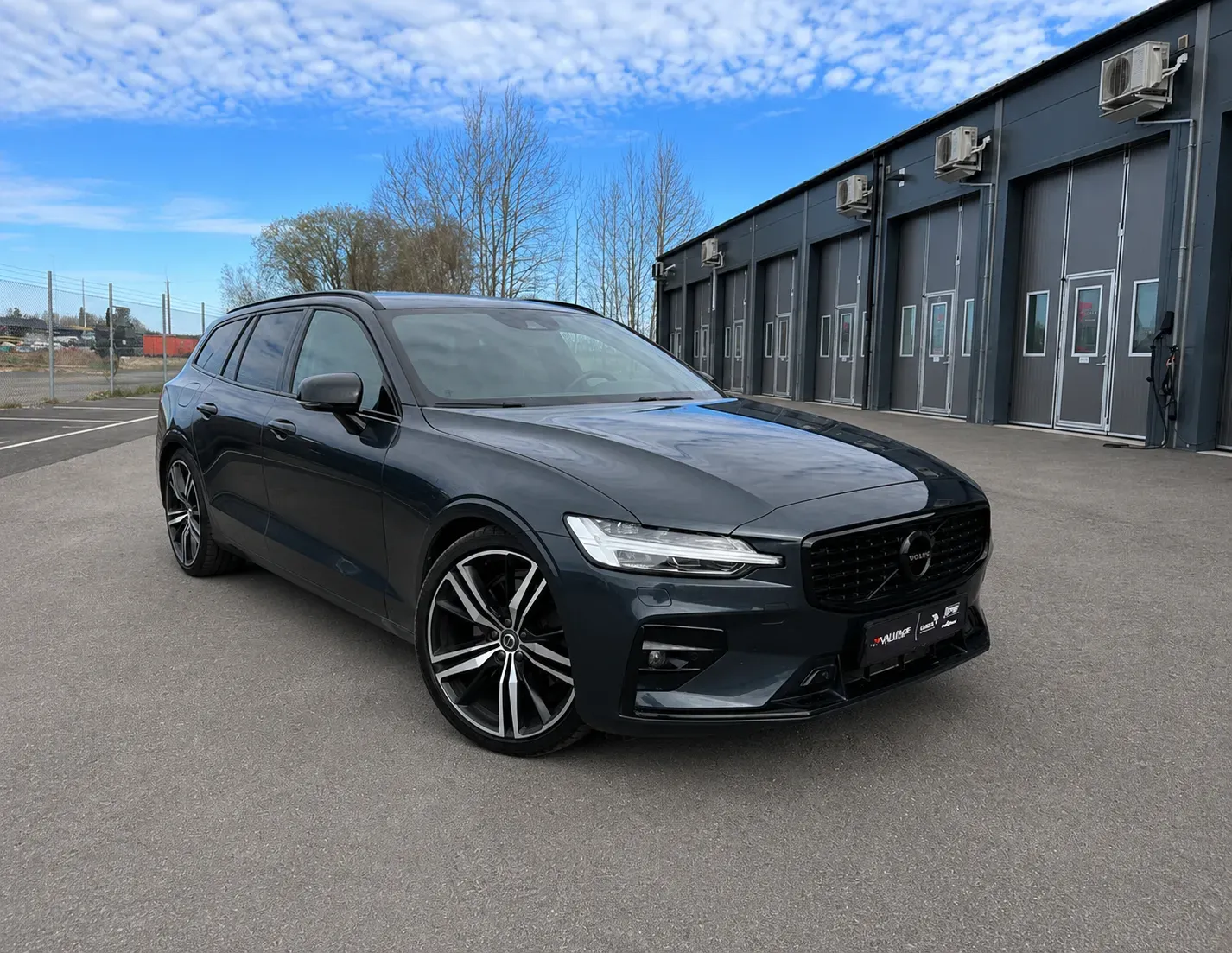 Mörkgrå Volvo V60 med tonade rutor efter professionell toning med solfilm utanför verkstad i Skövde.