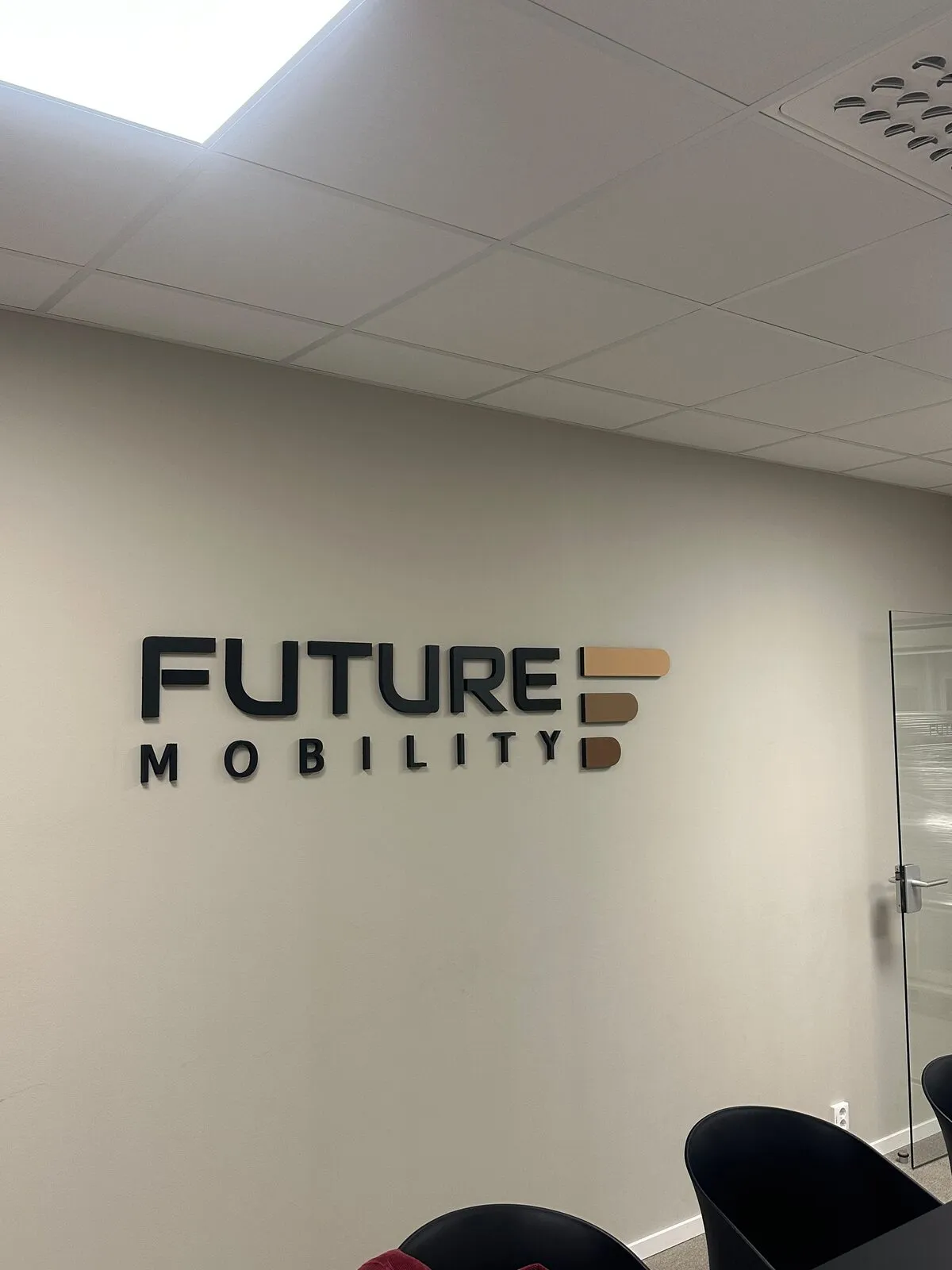 Future Mobilitys logotyp i upphöjda bokstäver på en kontorsvägg